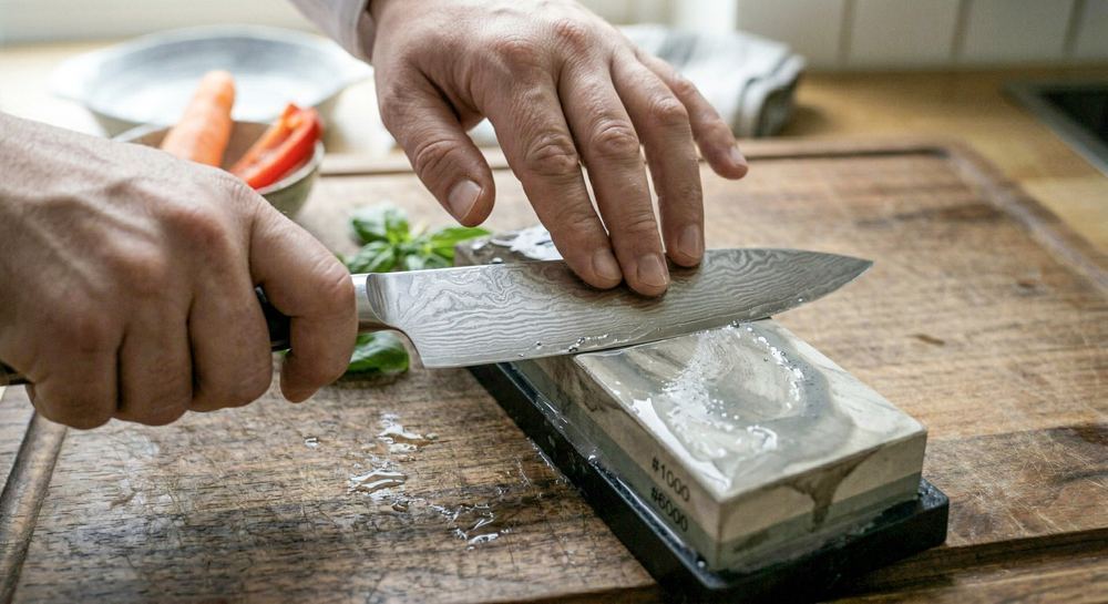 Knife being sharpened on a whetstone showing the correct 15-20 degree angle and stroke direction